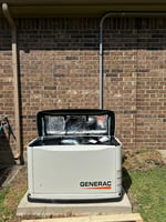 Generac standby generator installed beside a brick home by Adrian Electric