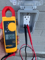 Electrician testing a GFCI outlet with a clamp meter